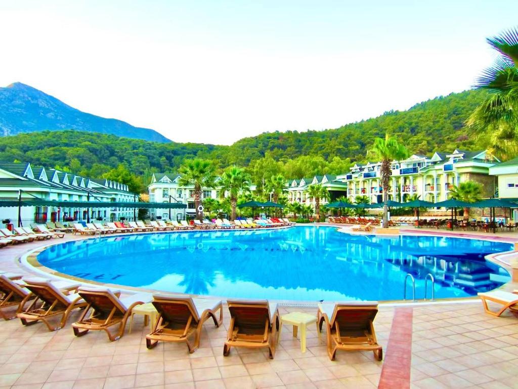 a large swimming pool with chairs and umbrellas at Green Forest Holiday Village in Oludeniz