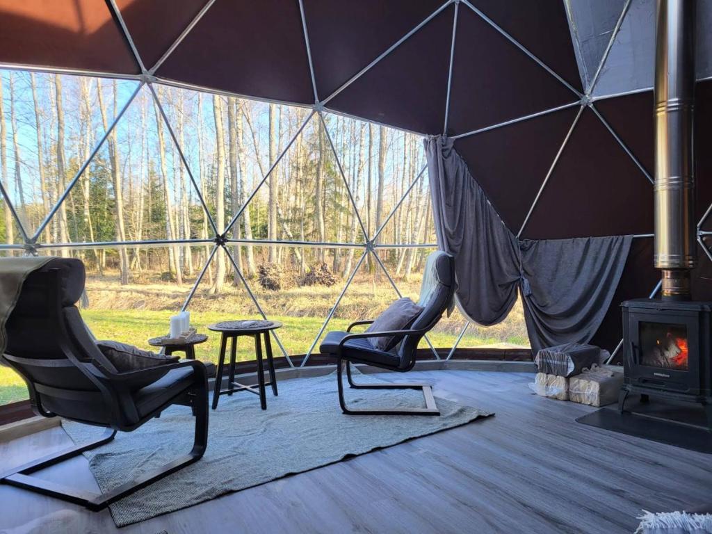 een tent met twee stoelen en een open haard bij Ozoli - Pirts / Viesunams 