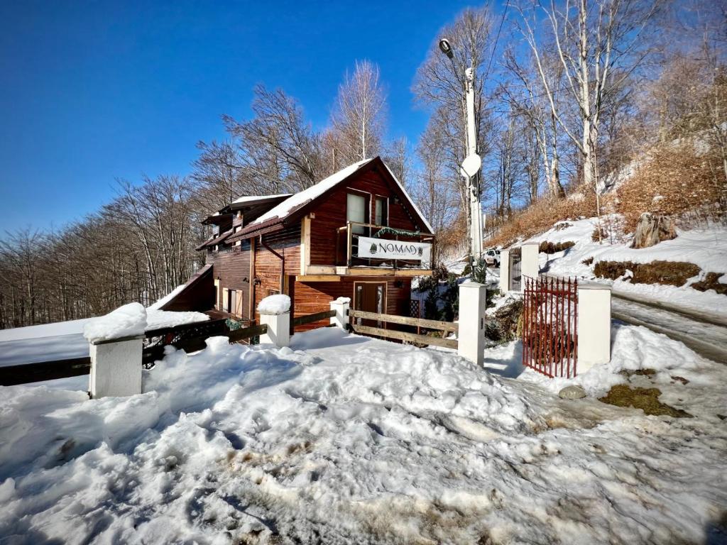 una baita di tronchi nella neve con un mucchio di neve di Chalet Nomad a Petroşani