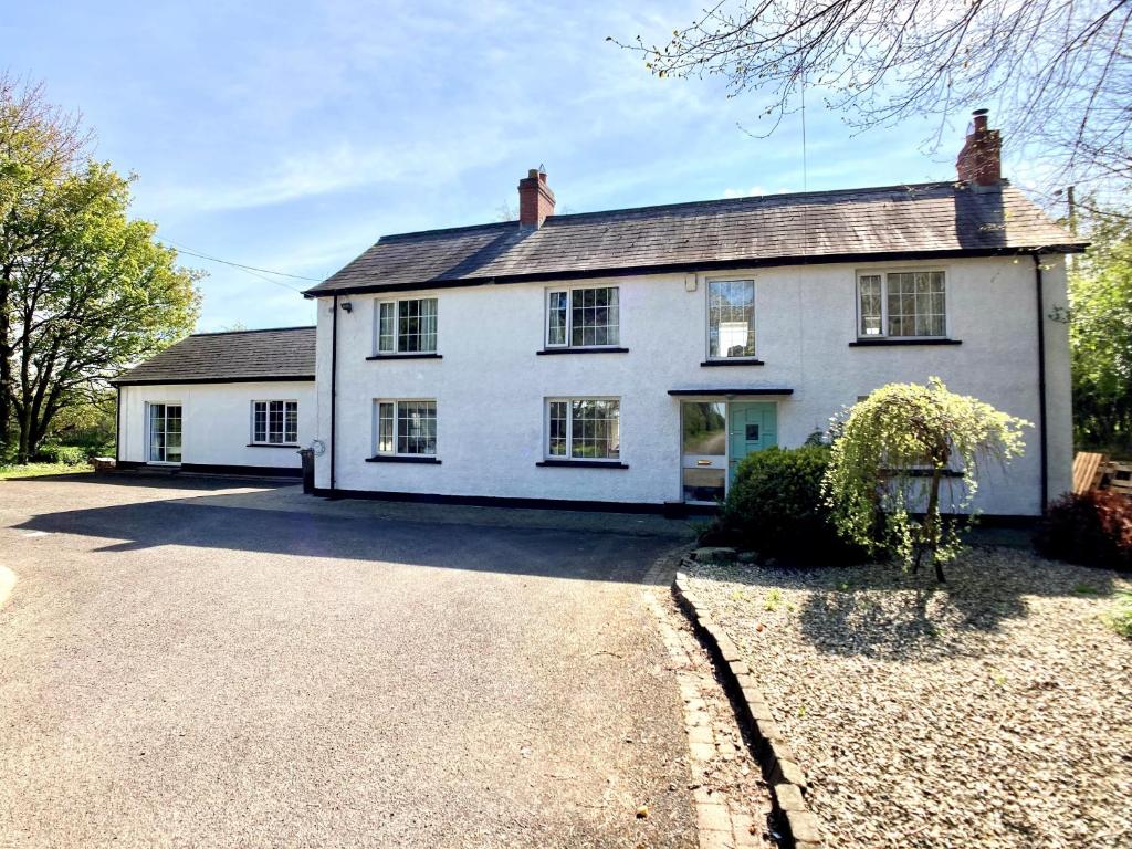 una casa blanca con una entrada delante de ella en Large Country Farmhouse with Garden and Stream, en Doagh