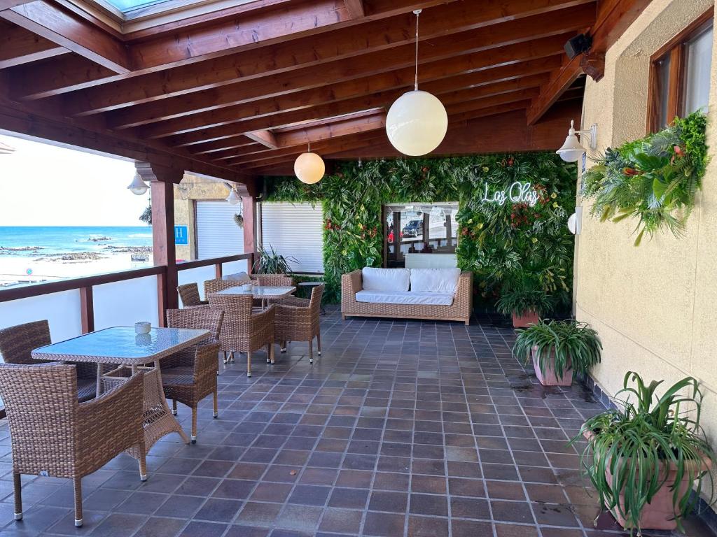 a patio with tables and chairs and a couch at Hotel Las Olas in Noja