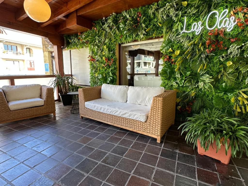 a patio with two wicker chairs and plants at Hotel Las Olas in Noja