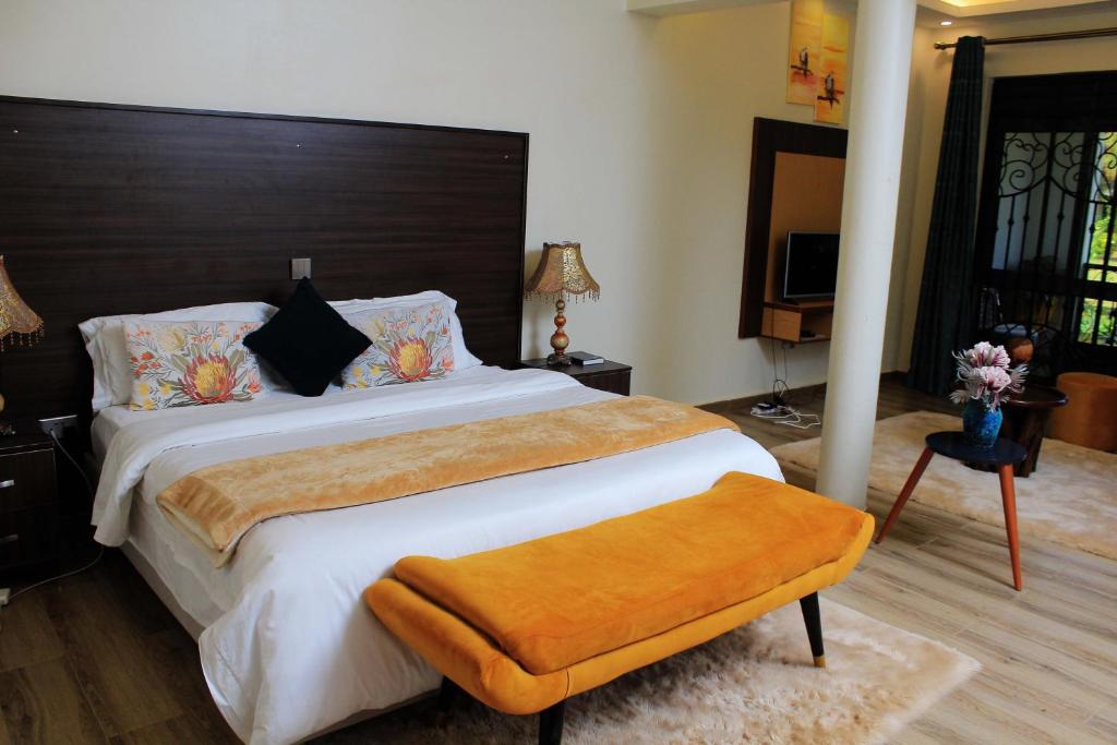 1 dormitorio con 1 cama grande y cabecero marrón en Mamikki Farm and Cottages, en Tororo