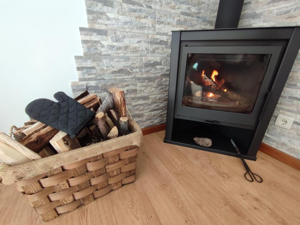 a fireplace in a living room with a basket of wood at Segredos da Montanha - Seia in Seia