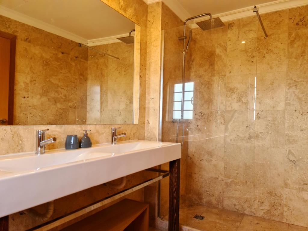 La salle de bains est pourvue d'un lavabo et d'une douche. dans l'établissement Homefield Gardens by HnM, à Conceição
