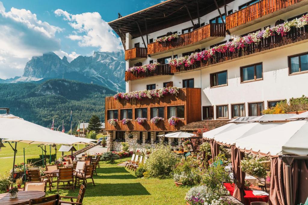 un hôtel dans les montagnes avec des tables et des chaises dans l'établissement Hotel Mirage, à Cortina dʼAmpezzo