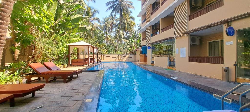 ein Pool in einem Hotel mit Stühlen und einem Gebäude in der Unterkunft Sia Signature Calangute in Calangute