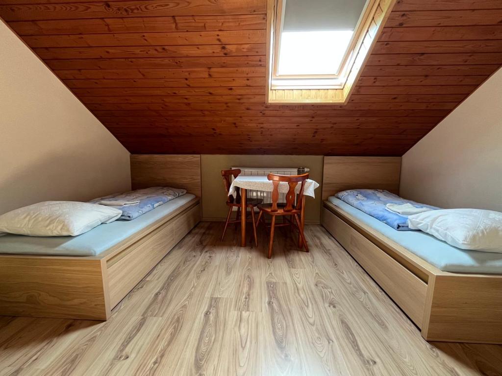 een kamer met 2 bedden, een tafel en een raam bij Penzión D+D in Zázrivá