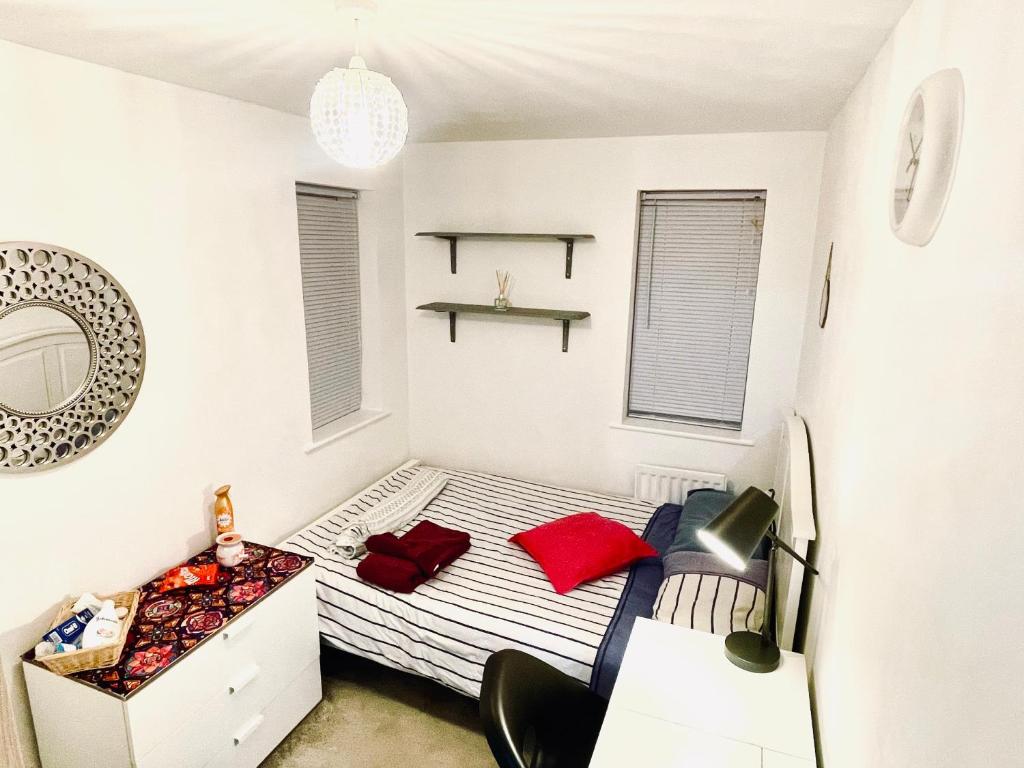 Private room in BS14 في بريستول: غرفة نوم صغيرة مع سرير مع وسائد حمراء