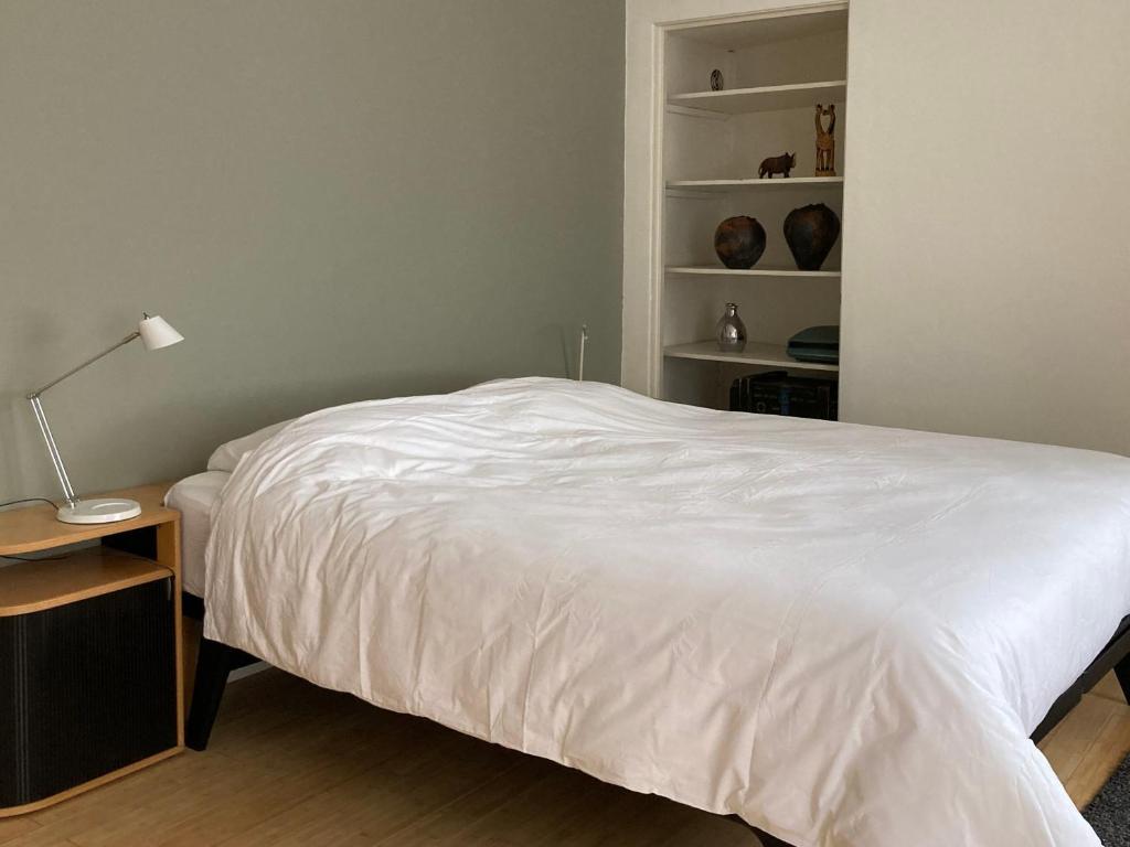een slaapkamer met een wit bed, een bureau en planken bij B&B De Juliaantjes in Maastricht