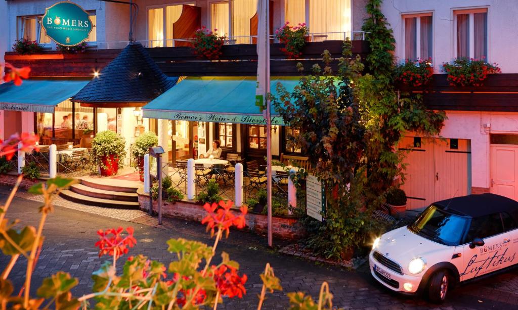 une voiture blanche garée devant un restaurant dans l'établissement Ringhotel Bömers Mosel Landhotel, à Alf