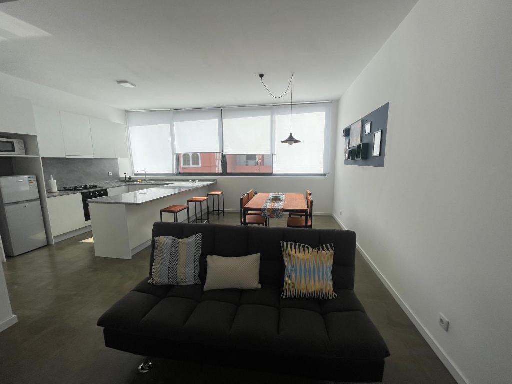 a living room with a black couch and a kitchen at Tia Nita Apartamentos in Mindelo