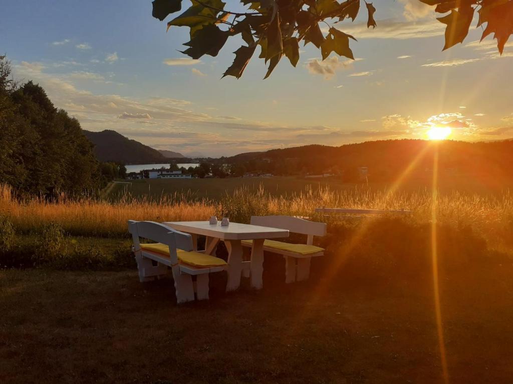 a table and benches with the sunset in the background at Appartement Georg in Unterburg am Klopeiner See