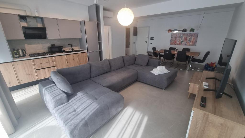a living room with a gray couch and a kitchen at Anateea by the Sea in Mamaia