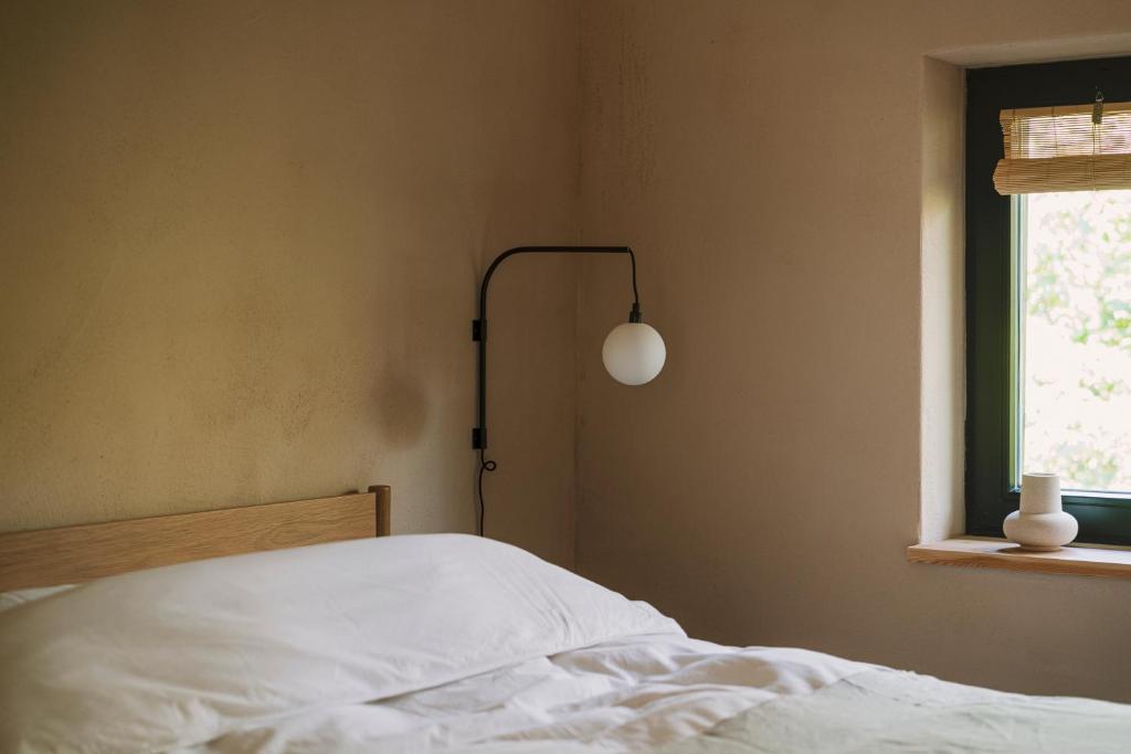 a bedroom with a bed with a lamp and a window at Gniazdowo nad rzeką - dom z sauną i masażem in Łochów