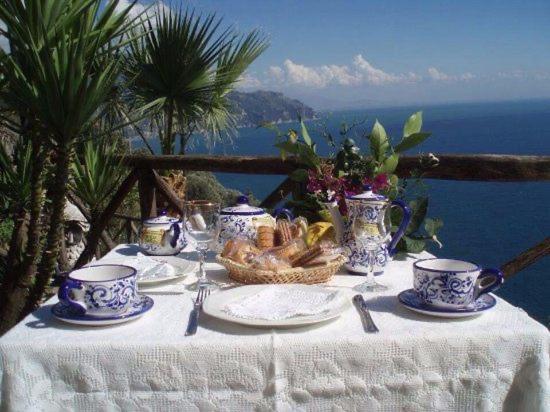 a table with a white table cloth and blue and white cups at Villa Hermosa Costiera Amalfitana in Amalfi