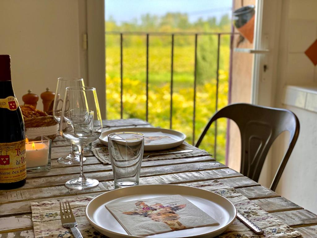 a wooden table with plates and wine glasses on it at Mas de la Sacristière in Jonquerettes