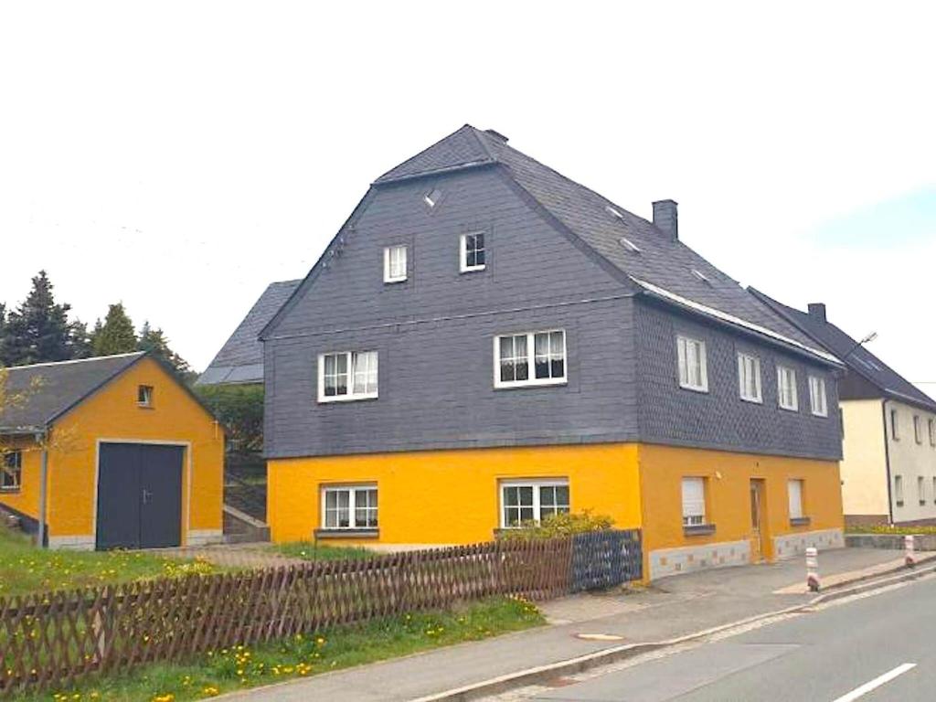 une maison jaune et orange sur le côté d'une rue dans l'établissement Spacious Holiday Home in Bärenstein with Garden, à Bärenstein