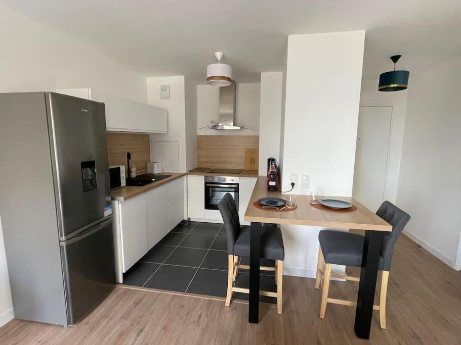 a kitchen with a table and chairs and a refrigerator at Superbe T2 proche de la Gare RER TGV Massy Palaiseau in Massy