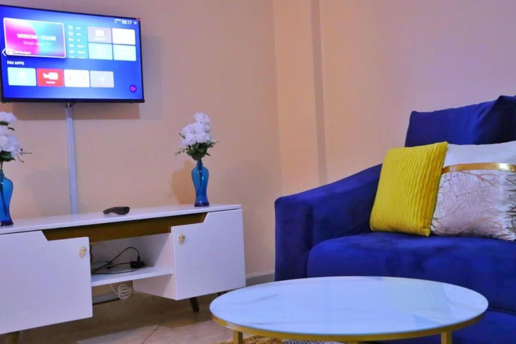 sala de estar con sofá azul y TV en Santaq villas apartment en Nairobi