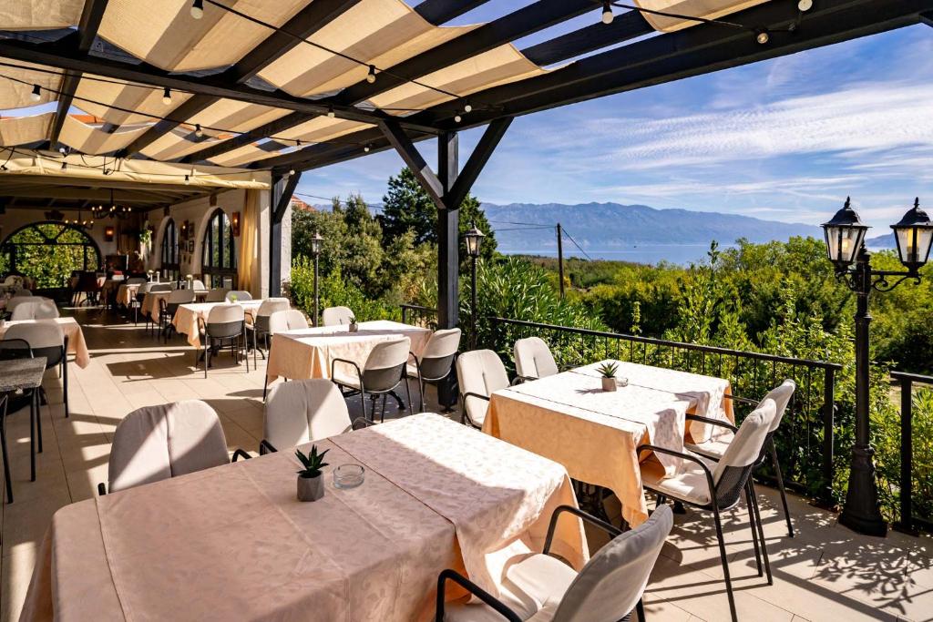 un restaurante con mesas y sillas blancas y un balcón en Pansion Lavanda Lopar en Lopar