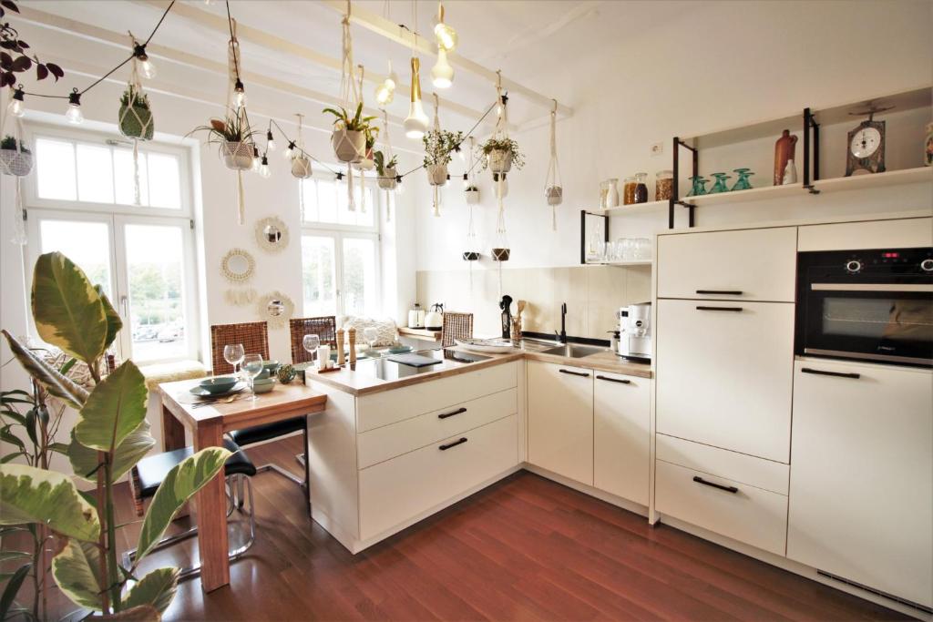 a kitchen with white cabinets and a wooden floor at EXKLUSIV home & business Deluxe Kregel Apartment 70qm in Leipzig