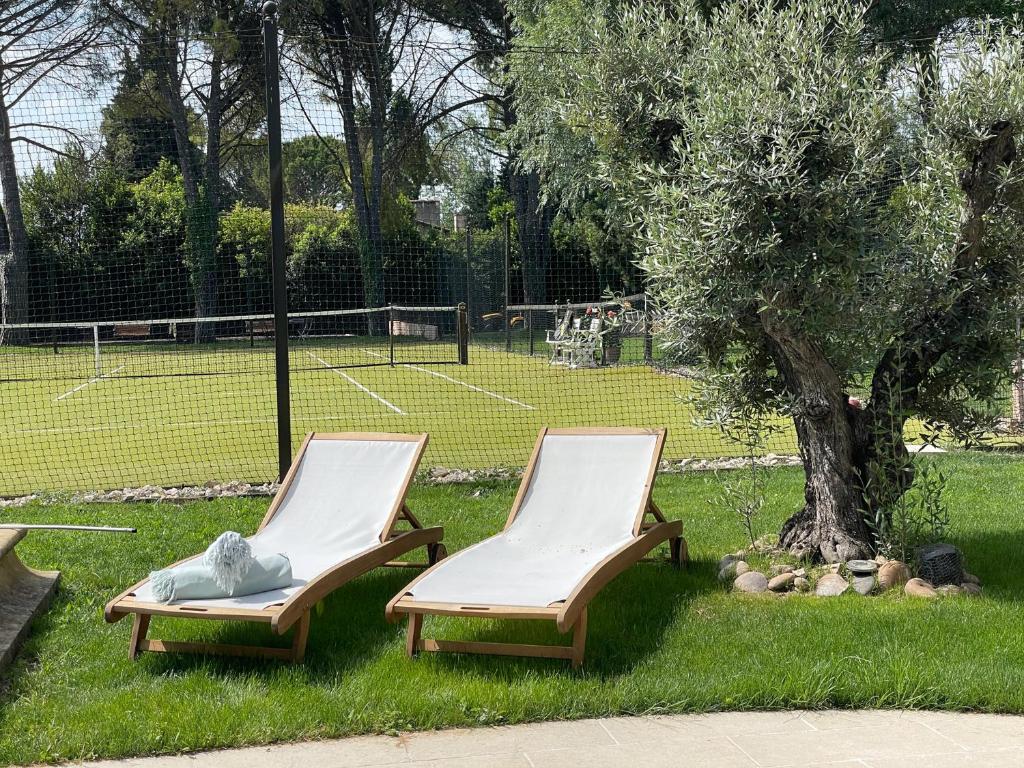 two chairs sitting in the grass next to a tennis court at Mas de la Sacristière in Jonquerettes