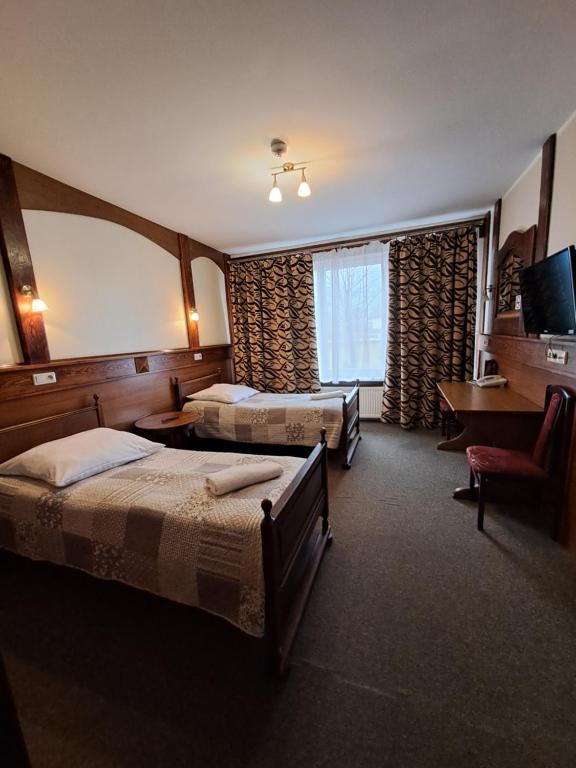 a hotel room with two beds and a television at Dworek staropolski in Poznań