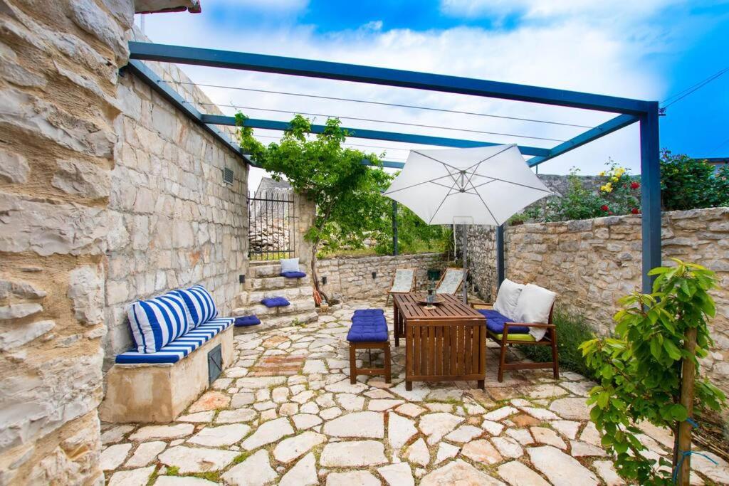 a patio with a table and chairs and an umbrella at Mala House - Šolta Island in Grohote
