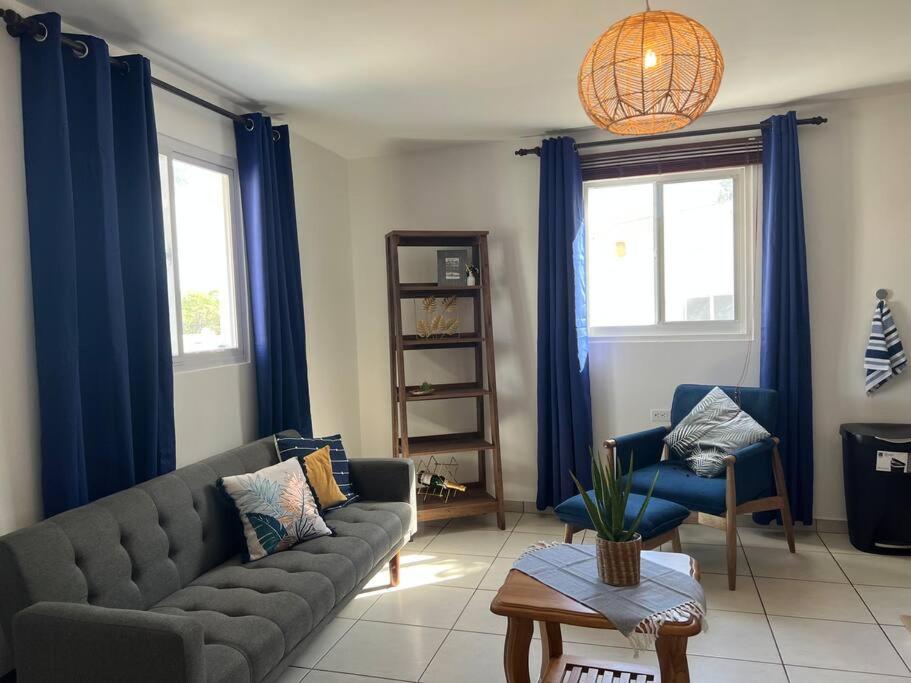 sala de estar con sofá y cortinas azules en Romantic place savaneta near several beaches, en Savaneta