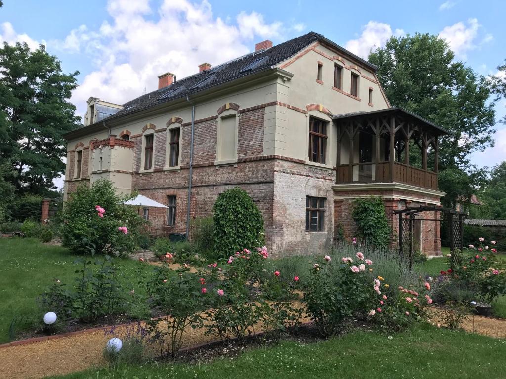 Une vieille maison en briques avec des fleurs dans la cour dans l'établissement Romantische Ferienwohnung im Herrenhaus Wüstenhain Spreewald, à Vetschau/Spreewald