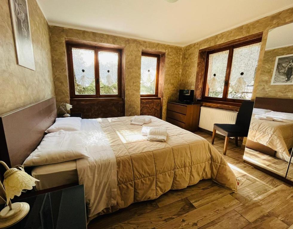 a bedroom with a large bed and two windows at San Luigi - Rooms & Apartments in Campodolcino