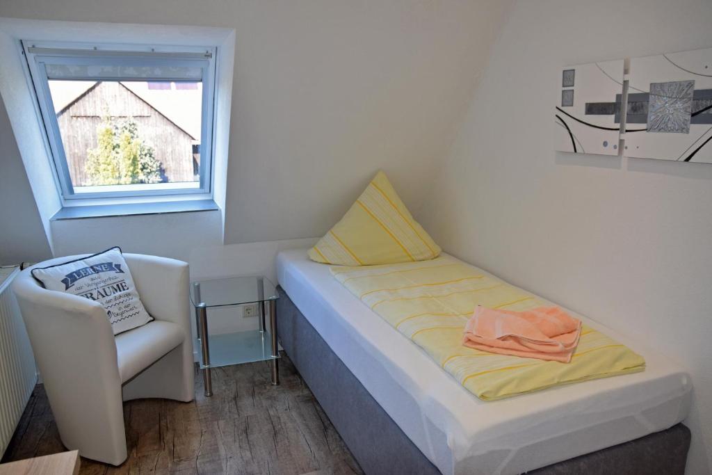1 dormitorio pequeño con 1 cama y 1 silla en RATAGS Kunsthandwerkerhaus, en Langenwolmsdorf