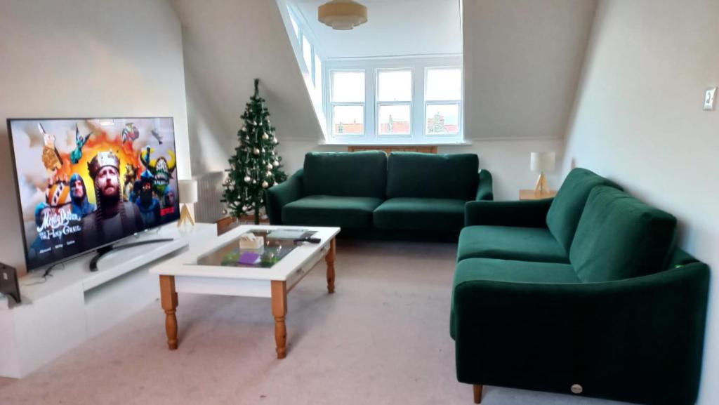 a living room with two green couches and a christmas tree at Falconhurst in Robin Hood's Bay