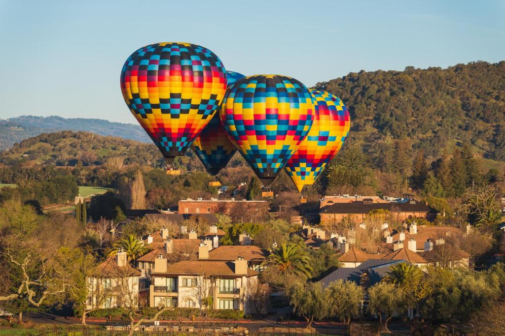 Dois balões coloridos de ar quente a voar sobre uma cidade em The Estate Yountville em Yountville