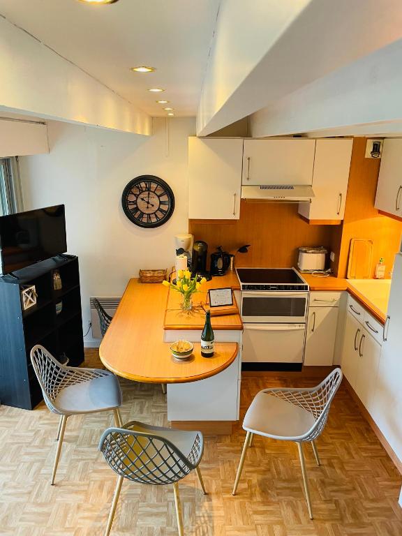 une cuisine avec une table, des chaises et une horloge dans l'établissement Appartement duplex hyper bien placé plages à 2 pas Carnac plage, à Carnac
