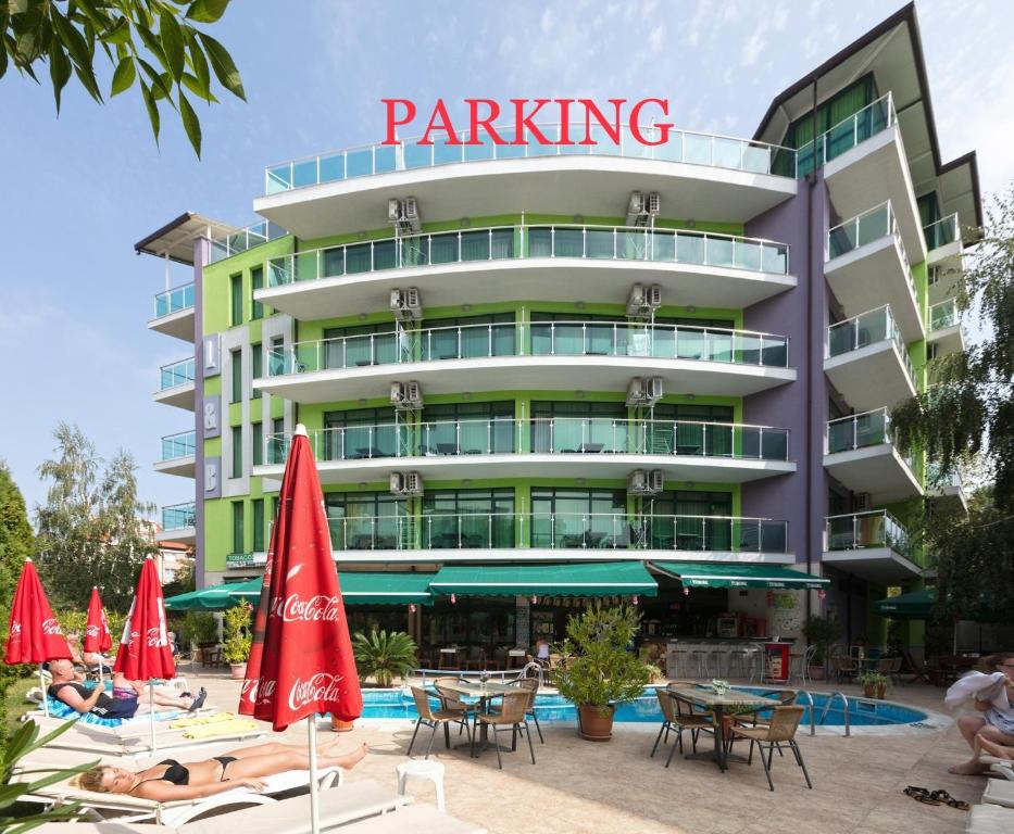 a hotel with chairs and umbrellas in front of a building at Hotel L&B- Free parking in Sunny Beach