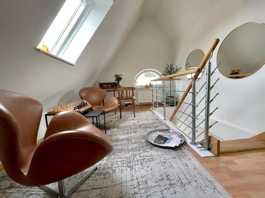 uma sala de estar com uma escada, cadeiras e um espelho em Modernes, familienfreundliches Apartment in Lübeck em Lübeck