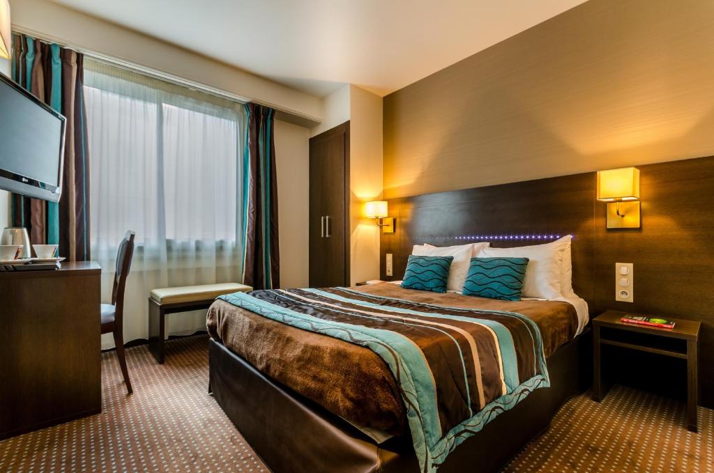 a hotel room with a bed and a television at Helgon Hotel - Lourdes Pyrénées in Lourdes