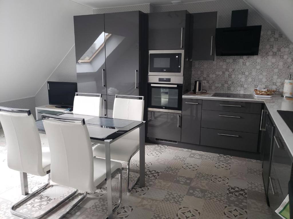 a kitchen with a table and white chairs in it at Ile Cigogne in Fouesnant