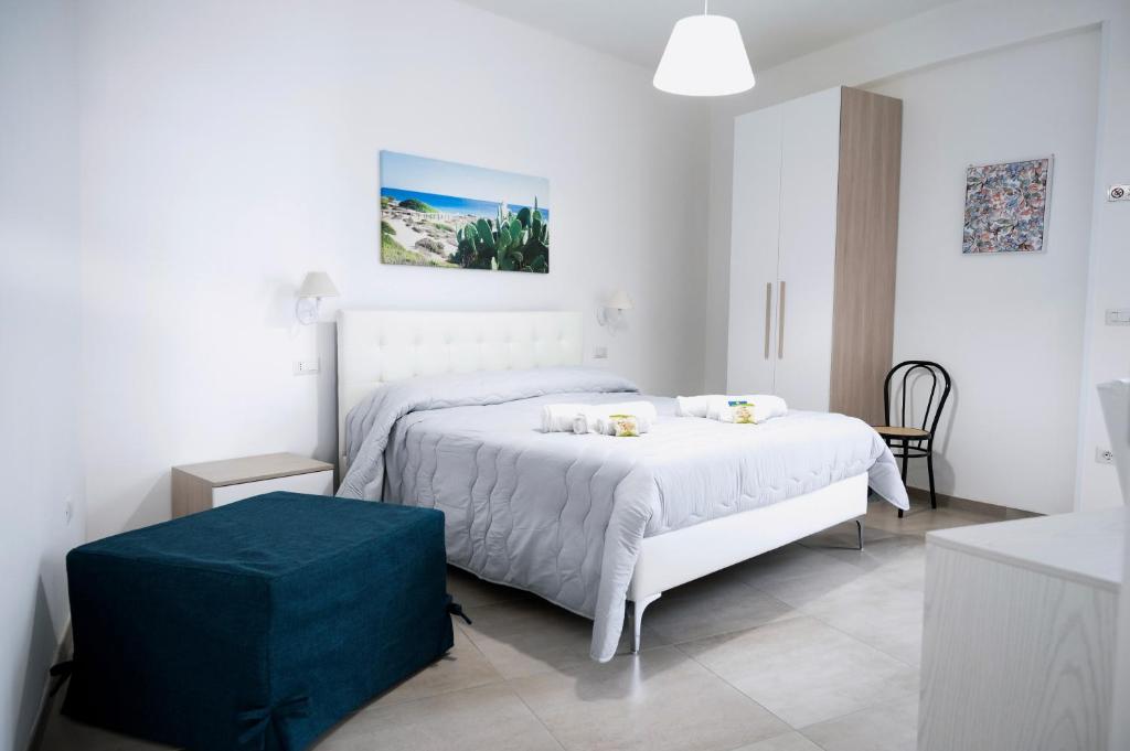 a white bedroom with a bed and a blue ottoman at Bed & Breakfast Terra d'Arneo in Leverano