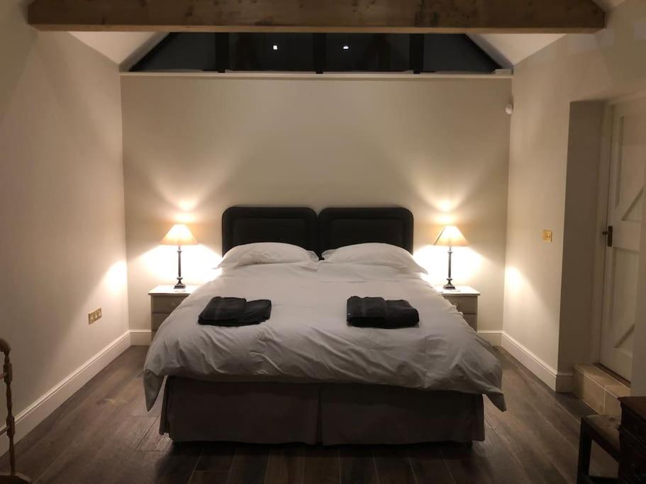 a bedroom with a large bed with two lamps on it at The Stables in Colchester