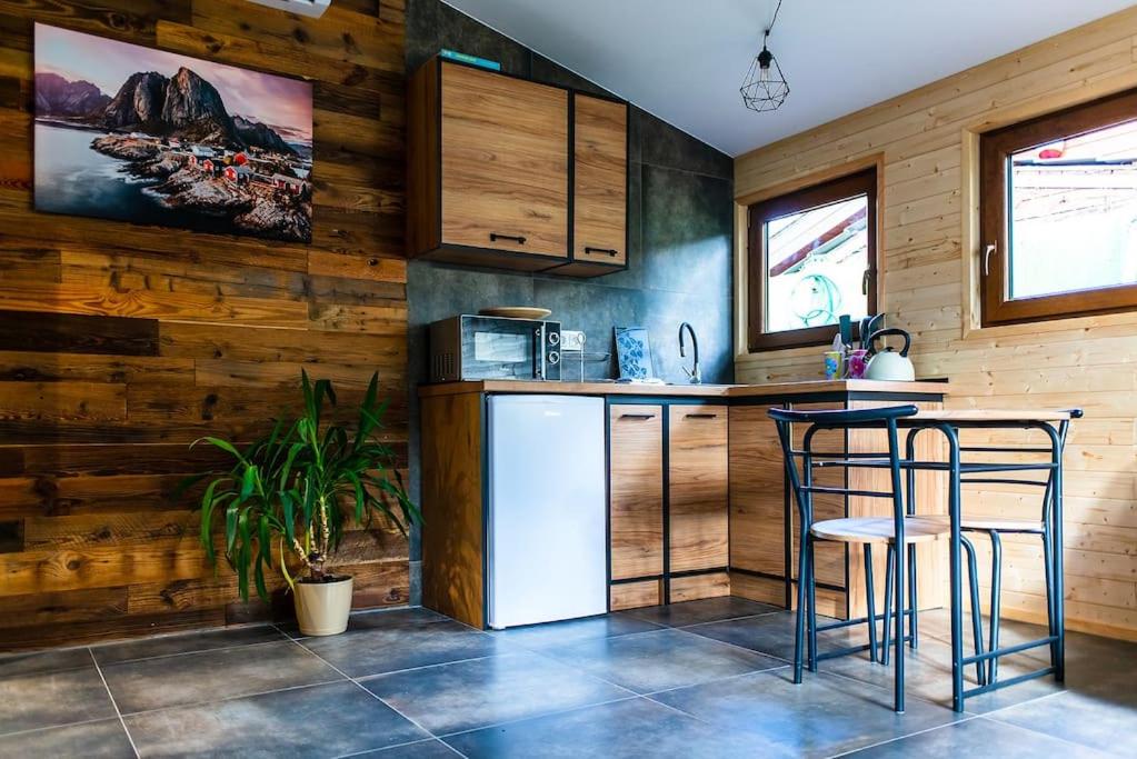 a kitchen with wooden walls and bar stools in it at Domek Trolla in Sieraków