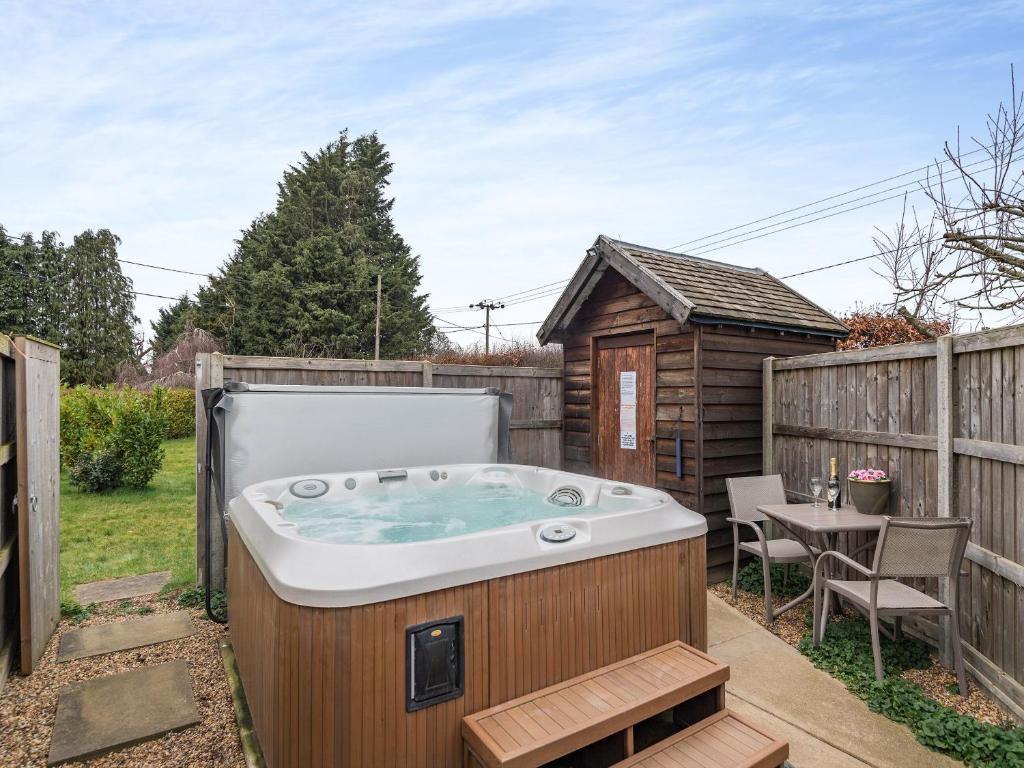 a hot tub in a backyard with a table and a fence at Hare Cottage in North Tuddenham