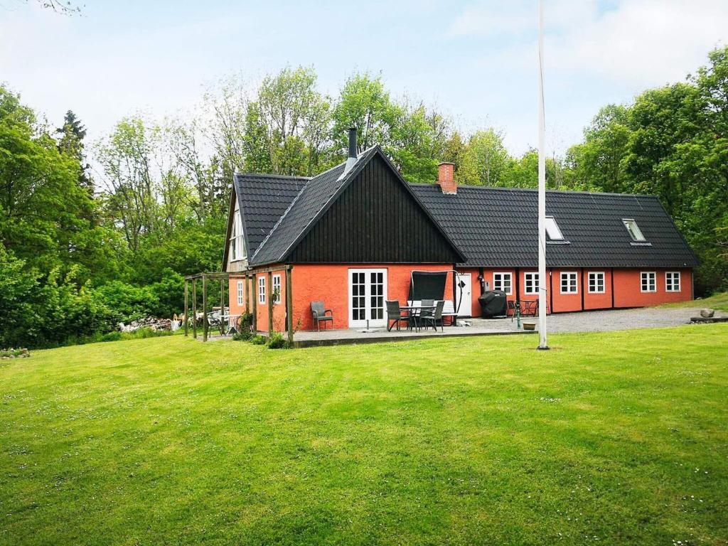 een rood huis met een zwart dak op een groen veld bij Holiday home Nexø XLIII in Neksø
