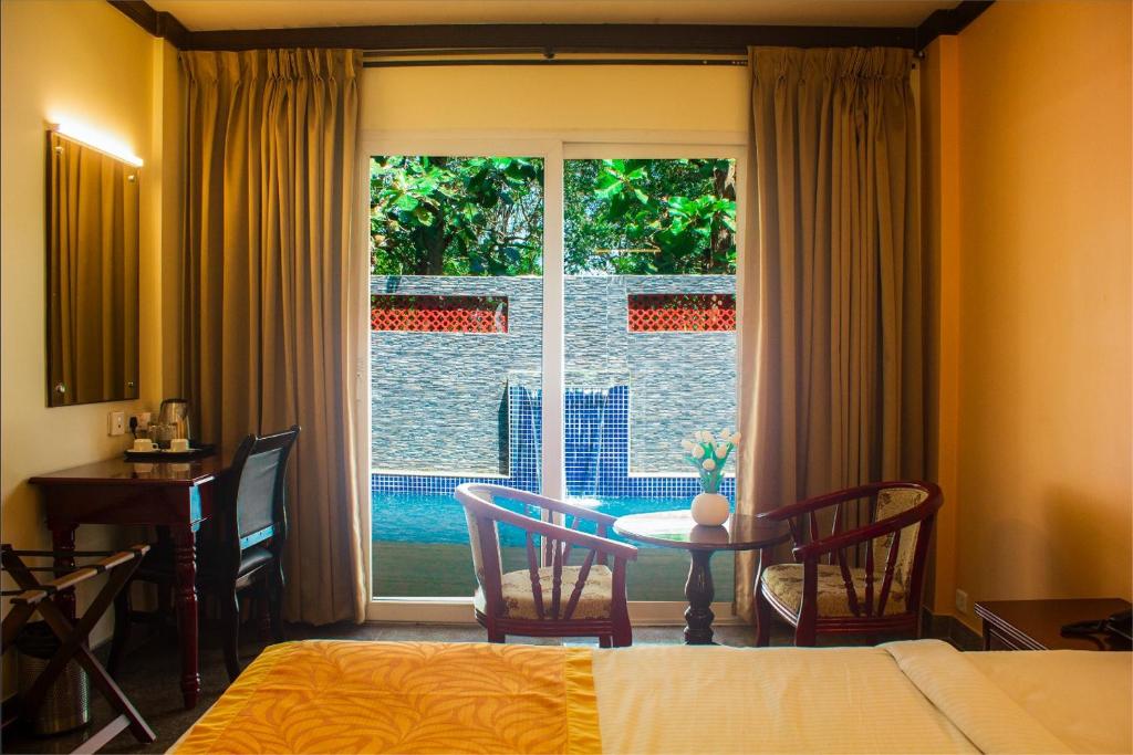 Schlafzimmer mit einem Bett, einem Tisch und einem Fenster in der Unterkunft Serene Sriperumbudur in Kāndūr