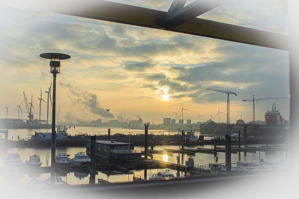a view from a window of a harbor at sunset at Hotel de Boegschroef in Delfzijl