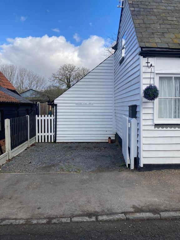 a white house with a fence next to it at Lime Tree Cottage in Tillingham