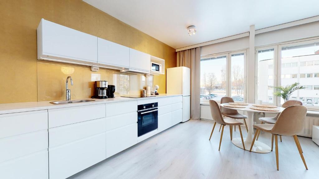 a kitchen with white cabinets and a table with chairs at Bellarova Apartments VI in Rovaniemi