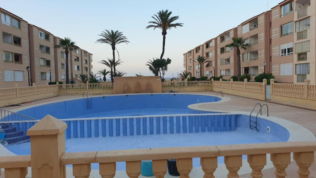 una gran piscina con palmeras y edificios en Oasis Paradise Apartment La Manga en La Manga del Mar Menor